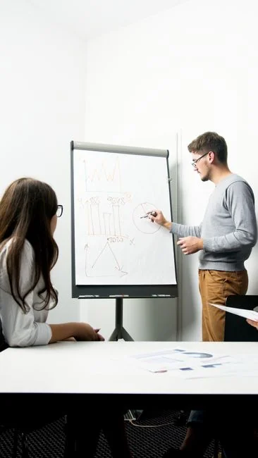 Overhead view of business chart with red notebook and colored pencils on table.